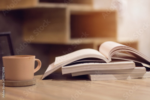 Close up stack of magazine or books with cup of coffee on wooden table in copy space concept.