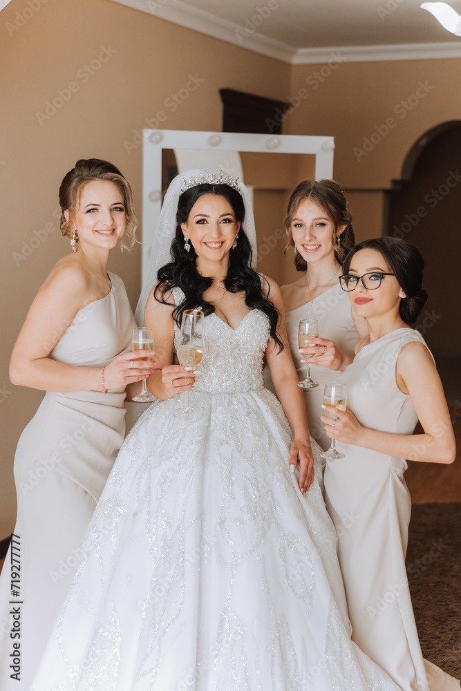 Naklejka premium Photo bride with her friends drinking champagne from glasses. Cropped shot of a beautiful young bride and her bridesmaids having champagne before the wedding.