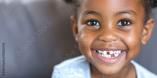 Portrait of smiling African American kid with white teeth on a blurred background. Healthy teeth, dentistry dental care positive people concept. The smile of a young happy elementary school girl photo