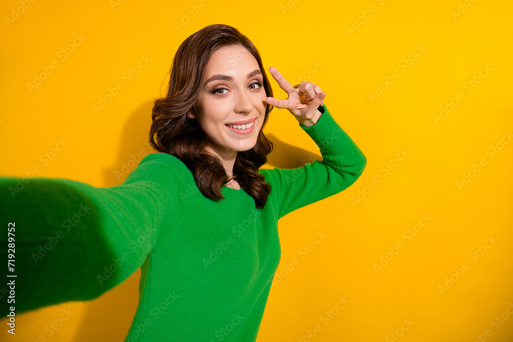 Selfie photo of young charming brunette curly haired girlfriend show v sign posing like a star blogger isolated on yellow color background Selfie photo of young charming brunette curly haired girlfriend show v sign posing like a star blogger isolated on yellow color background