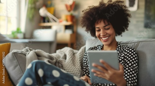 Digital Leisure: Smiling Woman Enjoying Tablet on Cozy Sofa at Home photo