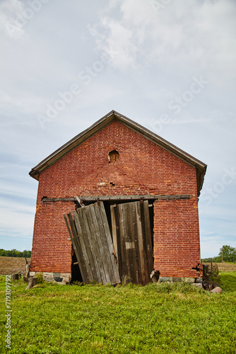Weathered Brick Barn with Decaying Doors in Countryside