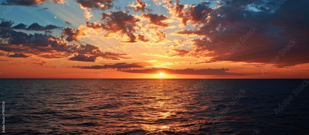 Fototapeta premium As the radiant sun descended towards the horizon, casting hues of orange and pink across the vast expanse of the sea.