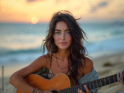 Girl playing guitar on the beach at sunset