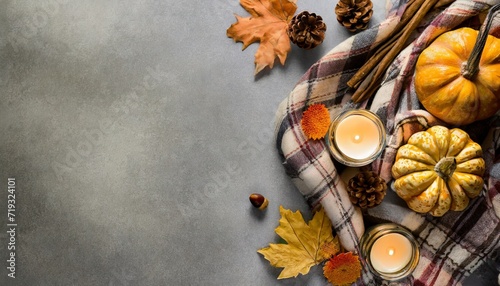 embrace the comfort of home in fall with this top view image cozy patchy plaid and autumnal attributes pumpkin candles pinecones and maple leaves create cozy setting for copyspace on grey backdrop photo