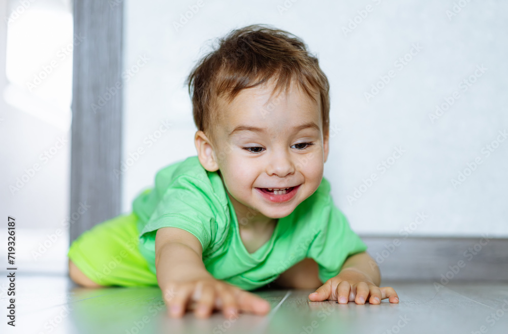 Little boy is lying on the floor and playing with his hands