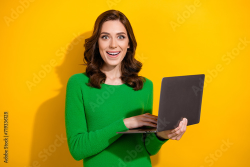 Photo of astonished pretty lady hold netbook unbelievable online shop offer isolated on yellow color background
