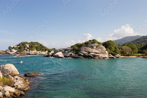 Big rocky mountains with tropical jungle vegetation in middle of blue turquoise caribbean sea with tropical jungle mountains at background