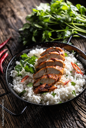 Grilled chicken breast served in a pan with jasmine rice and chili peppers