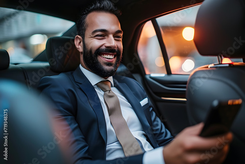 Successful middle-aged businessman sits in car with phone in his hands and smiles.