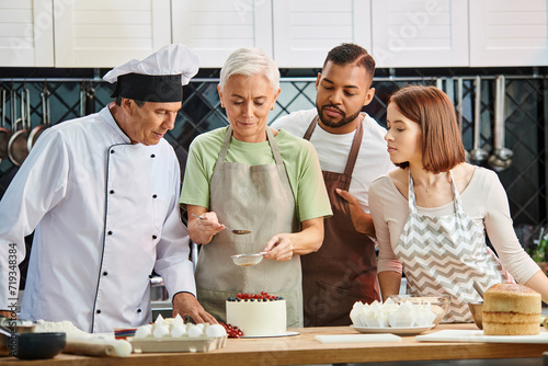 mature woman in apron decorating cake in front of chef and her diverse friends, cooking courses