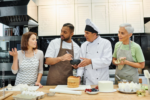 attractive diverse students and mature chef looking at young woman asking question, cooking courses