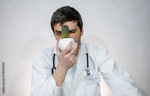 Doctor with stethoscope. Portrait of a doctor. Tired after work. A minute of rest time. Cactus in hand. Balance and peace