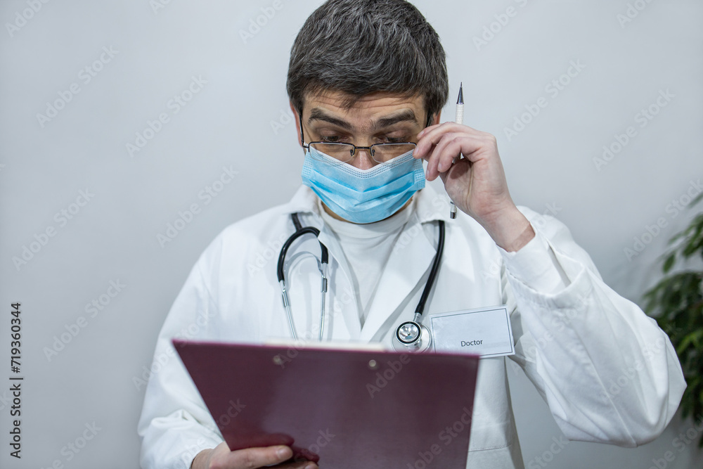 Doctor writing on clipboard. Doctor with mask and stethoscope. Portrait of a doctor Doctor writing on clipboard. Doctor with mask and stethoscope. Portrait of a doctor