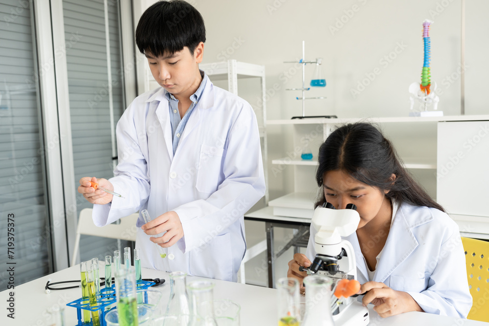 Asia kid boy in science uniform funny learning study science of use microscope and test chemical	
