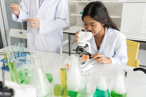 Asia kid girl in science uniform funny learning study science of use microscope and test chemical 