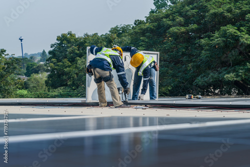 Worker Technicians are working to construct solar panels system on roof. Installing solar photovoltaic panel system. Men technicians carrying photovoltaic solar modules on roof. © ultramansk