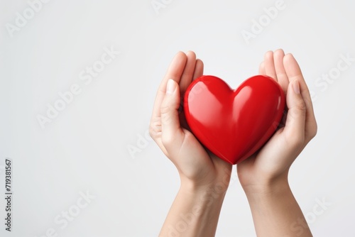 female hands holding an object in the shape of a red heart on a white background, concept for Valentine's Day, March 8, love. bright red glossy heart. free space for insertion