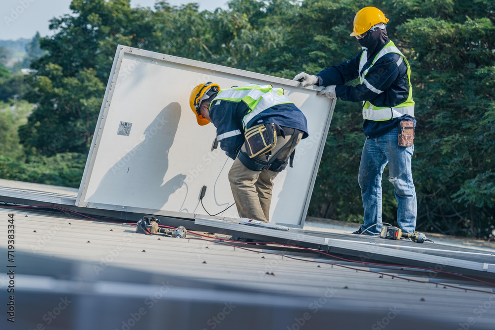 Fototapeta premium Worker Technicians are working to construct solar panels system on roof. Installing solar photovoltaic panel system. Men technicians carrying photovoltaic solar modules on roof.