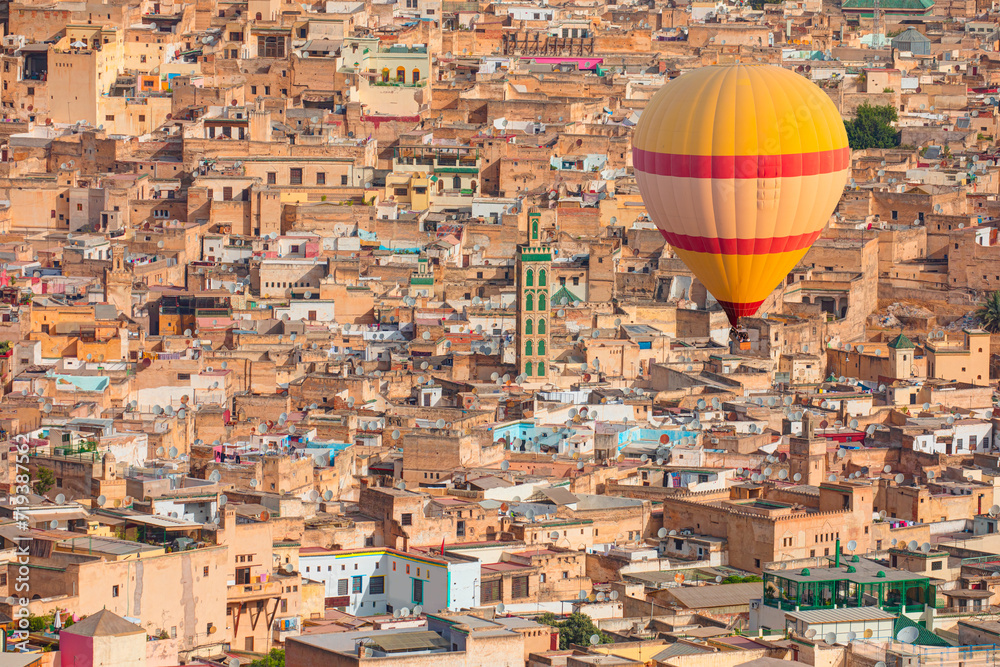 Fototapeta premium Hot air balloon flying over many buildings within the Medina of Fes, Morocco