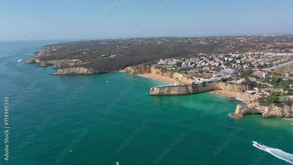 Aerial perspective of Algarve coastline. View of Armacao de Pera. Luxury hotels and urbanisation. Gloden beaches, turquoise water. High cliffs. Famous travel destination. Drone panning right