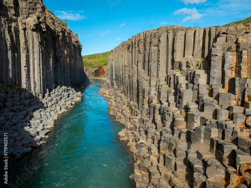 Canyon of magnificent basalt columns, high cliff with bright turquoise river, in North East Iceland, aerial shot. Studlagil, nature beauty concept.