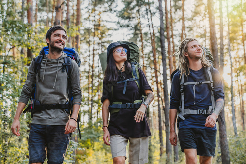 Tourist traveling concept. Smiling young group of people with backpacks having nature trip on weekend. Travelers on a track to mountains, exploring the nature © InsideCreativeHouse