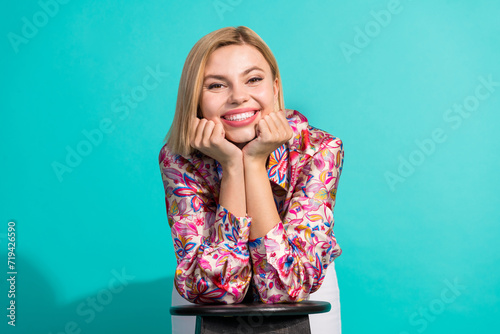 Photo portrait of nice young lady lean on chair dreamy smile wear trendy pink print garment isolated on cyan color background photo