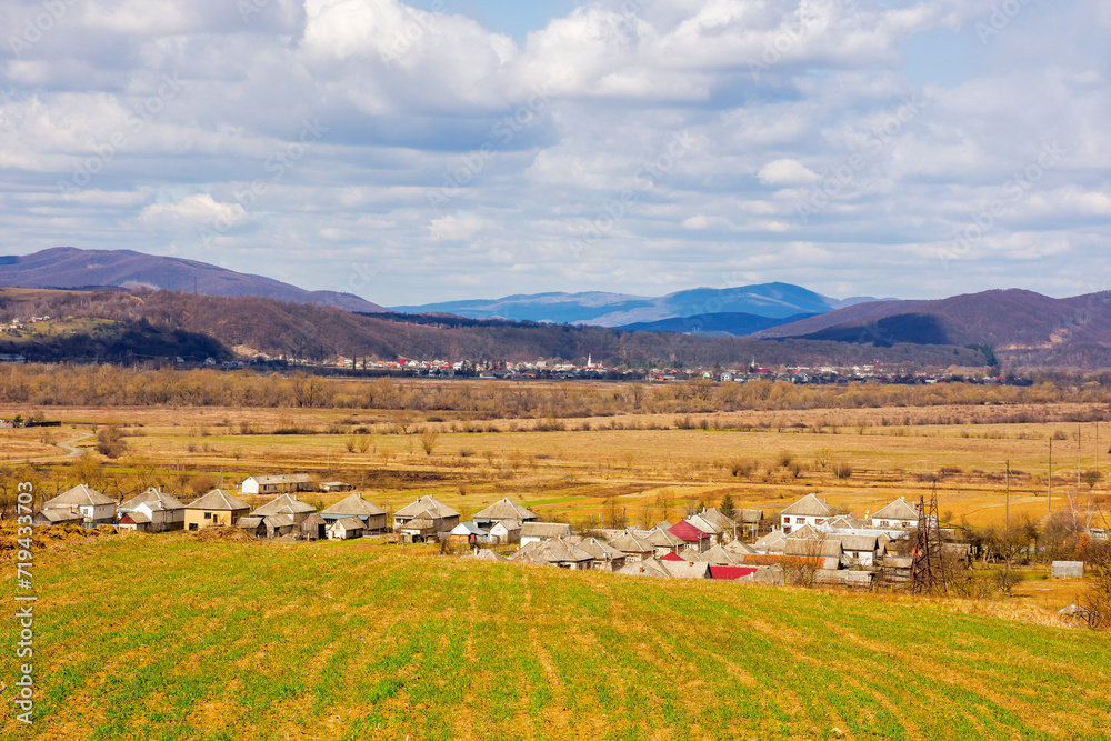 village in the wide valley in spring. mountainous rural landscape of ukraine. agricultural fields on the hills. clouds on the sky. wonderful countryside scenery of transcarpathia