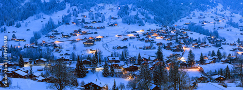 Panorama view of Grindelwald villages with wooden chalets covered with snow in cold winter season at the blue hours in Swiss Alps