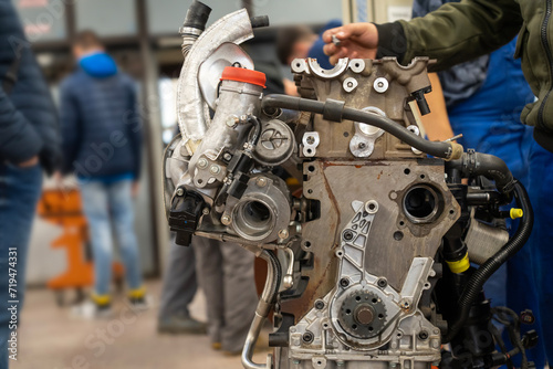 Auto mechanics assembling a disassembled car engine in a workshop