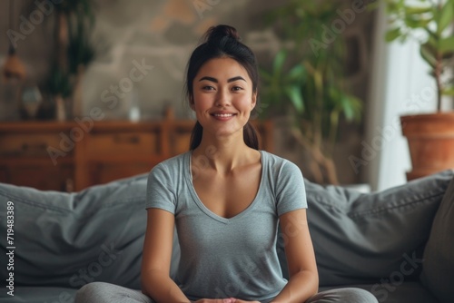 A woman sitting on a couch with a smile on her face. This image can be used to depict happiness and relaxation © Fotograf