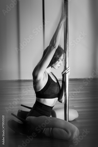 A young girl sitting on the floor concentrated before dancing. Black and white photo with space for advertising text.