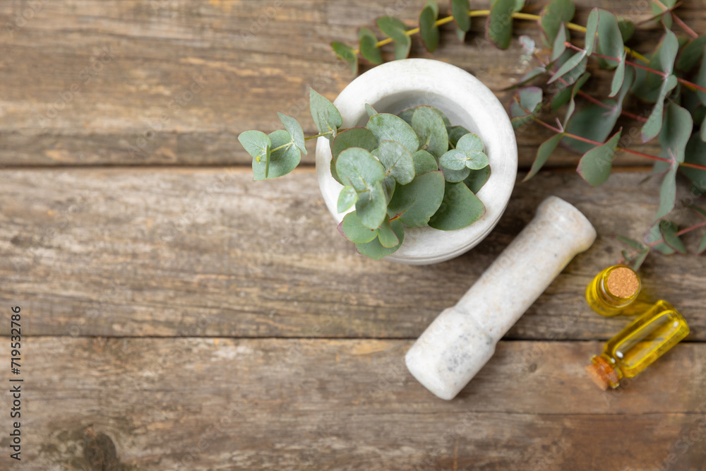 Eucalyptus leaves and mortar on a wooden background.Spa concept.Ingredients for alternative medicine and natural cosmetics. A bottle of essential oil and a bunch of eucalyptus. Organic skin care Eucalyptus leaves and mortar on a wooden background.Spa concept.Ingredients for alternative medicine and natural cosmetics. A bottle of essential oil and a bunch of eucalyptus. Organic skin care