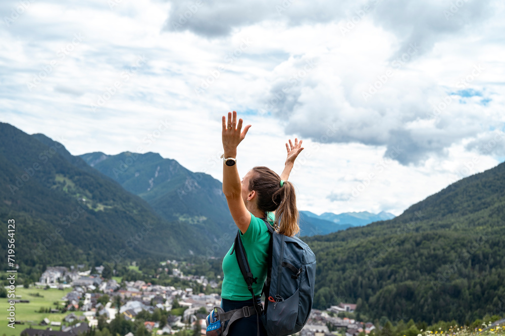Young hiker standing with her arms raised above a village view Young hiker standing with her arms raised above a village view