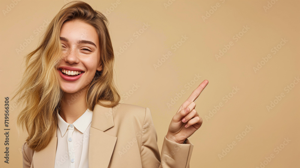 A blond young woman, against a beige background, is pointing with her index finger to the side. It's a banner featuring the girl pointing to a product for a website or advertisement. A blond young woman, against a beige background, is pointing with her index finger to the side. It's a banner featuring the girl pointing to a product for a website or advertisement.