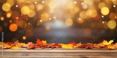 Autumn-themed wooden table top with bokeh light and colorful leaves on a blur background.