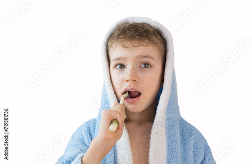 small child, boy in a blue terry robe with a toothbrush on white. A child brushes his teeth. Healthcare and dental care