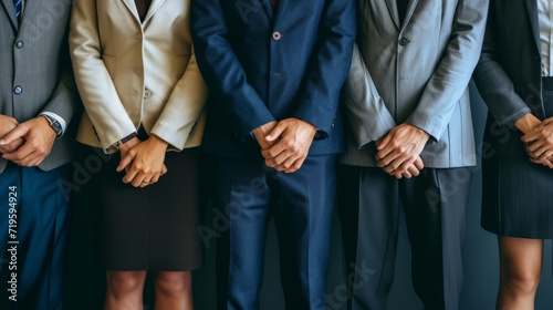 Group of professionals, standing in a row, each with their hands clasped in front of them