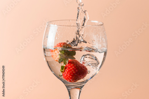 The strawberry falls into the glass and splashes, the bottom is uniform and salmon-colored.