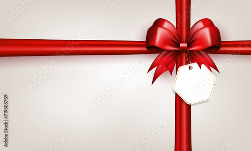 3d red bow with horizontal and vertical silk ribbons and paper label tag on white background with copy space. Scarlet bow with crossed tapes as gift box wrap or greeting card with empty place for text