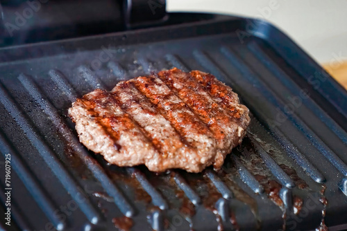Cooking burger beef patty on a hot frying pan close up. Preparing burger, homemade. Grocery product advertising, menu.