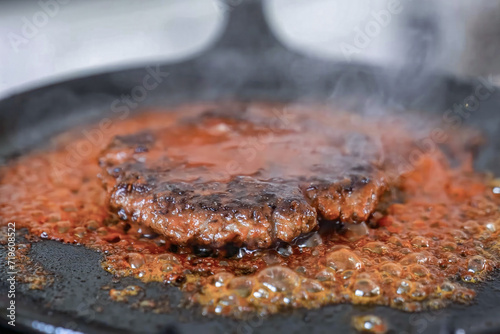 Cooking burger beef patty on a hot frying pan close up. Preparing burger, homemade. Grocery product advertising, menu.