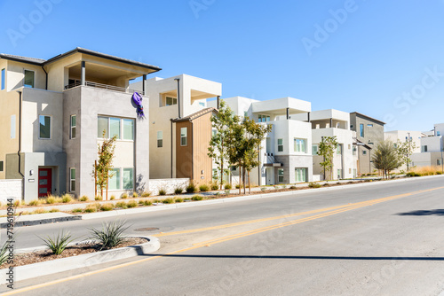 Row of new detached houses along a street in a housing development in California on a clear autumn day