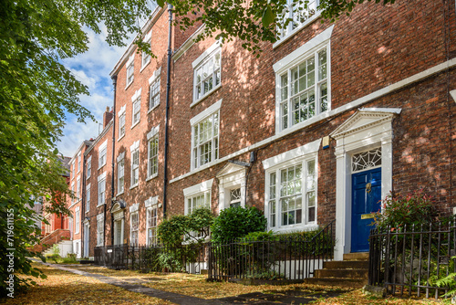 Row of renovated tradional British brick town houses with colourful wooden front doors in a city centre on a sunny summer day photo