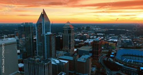 Approaching the group of beautiful skyscrapers in the uptown of Charlotte, NC, USA. Splendid orange sky over the scenery of a city. Top view.