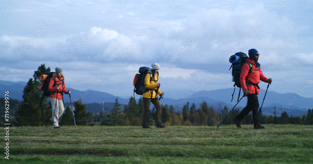 Full shot of African American man with Caucasian woman walking along trail in mountains in autumn. Multiethnic couple of tourist during trek or expedition to mountains on vacation. Active leisure. Full shot of African American man with Caucasian woman walking along trail in mountains in autumn. Multiethnic couple of tourist during trek or expedition to mountains on vacation. Active leisure.