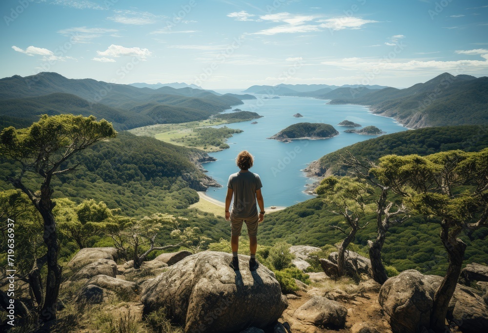 A lone figure takes in the breathtaking vista of the rugged mountain range, surrounded by the tranquil waters and lush greenery of the summer wilderness A lone figure takes in the breathtaking vista of the rugged mountain range, surrounded by the tranquil waters and lush greenery of the summer wilderness