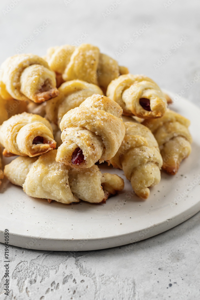 Homemade bagel cookies with dried fruits and walnuts on white plate on gray table. Sweet croissant cookies Homemade bagel cookies with dried fruits and walnuts on white plate on gray table. Sweet croissant cookies