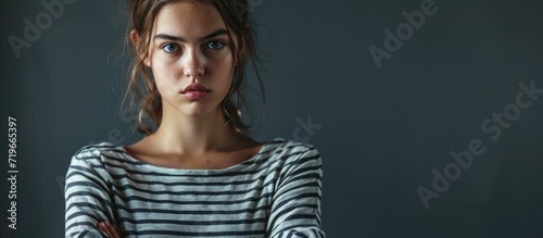 Young teenager girl wearing casual striped t shirt skeptic and nervous disapproving expression on face with crossed arms negative person. Copy space image. Place for adding text photo